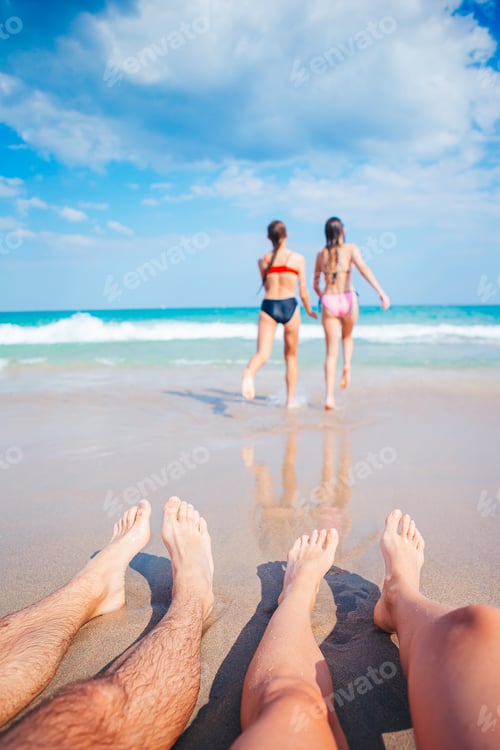 Preview: Closeup of the feet of family on the white sandy beach. Children play on the beach in shallow water