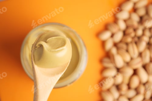Preview: Creamy pistachios nut butter spread with wooden spoon and nuts nearby