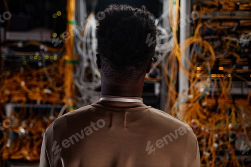 Back view black young man as system administrator looking at servers