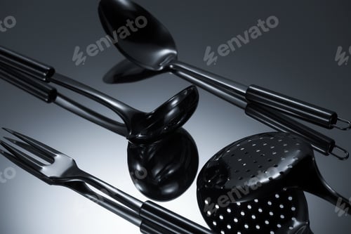 Preview: close-up view of shiny stainless steel utensils reflected on grey