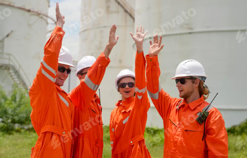 Preview: Team of workers celebrating during a sunny day at an industrial site