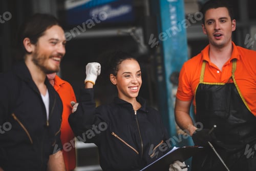 Preview: Group of young and senior car mechanics in garage wearing uniform enjoying and celebrating