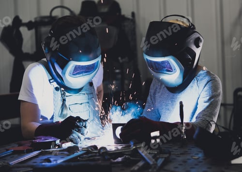 Preview: A female welder teaches a child how to weld - metal sparks fly and smoke is created