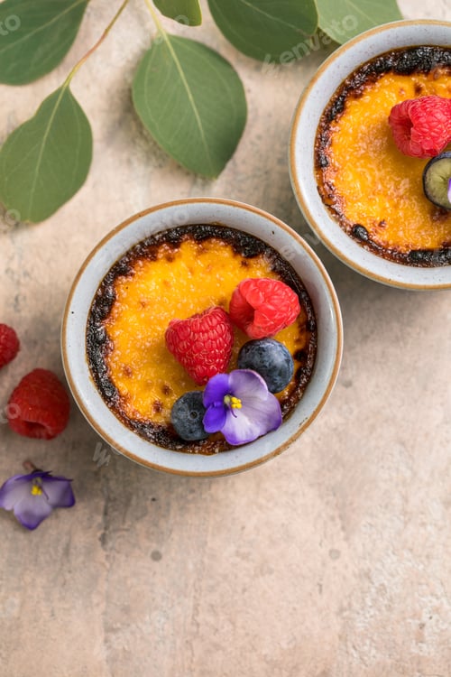 Preview: Creme brulee. French vanilla cream dessert with caramelised sugar and berries, selective focus.