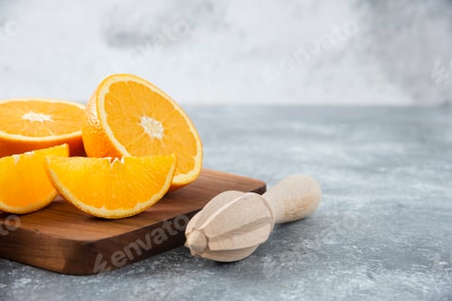 Preview: Sliced orange fruits with a wooden reamer on a wooden board