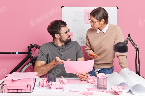 Preview: Two young woman and man coworkers look angrily at each other blame for mistake pose at modern office