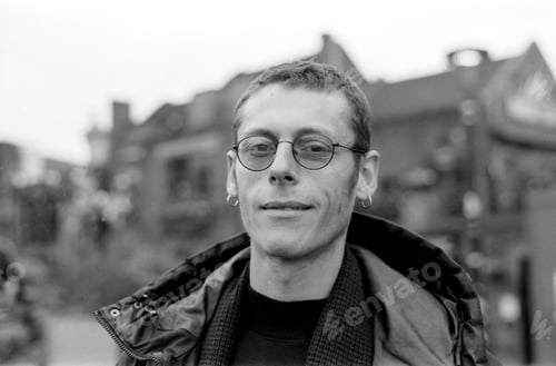 Preview: Young man wearing glasses is smiling outdoors in black and white analog photo
