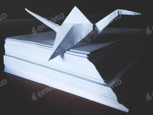 Preview: Folded paper origami crane on stack of paper
