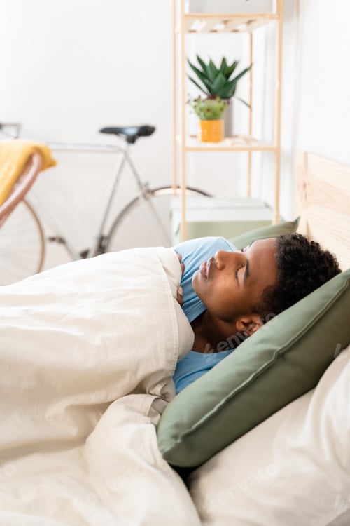Preview: Young man lying in bed sleeping on sunday morning.