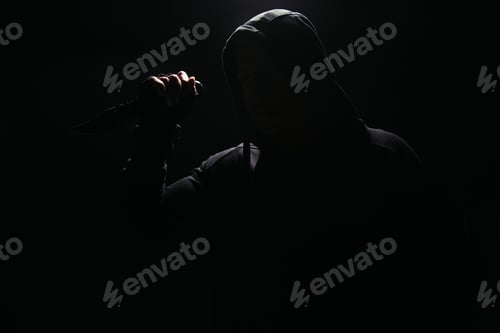 Preview: Silhouette of bandit in hoodie holding knife isolated on black