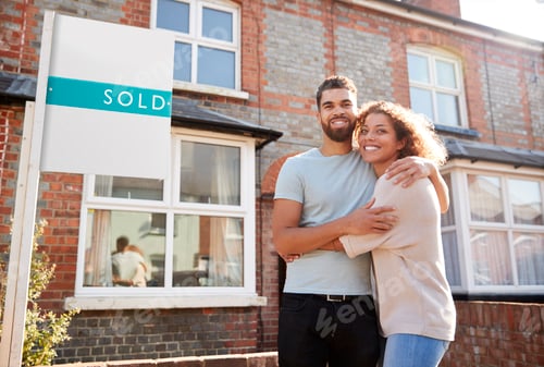Preview: Portrait Of Excited Couple Standing Outside New Home With Sold Sign