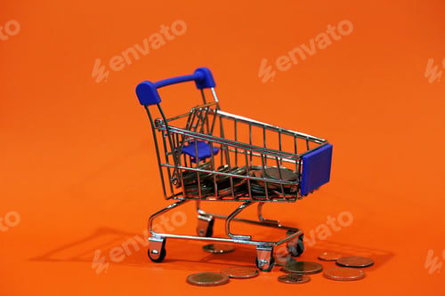 Preview: Concept of finance : Money, Coins in shopping cart closeup orange texture background