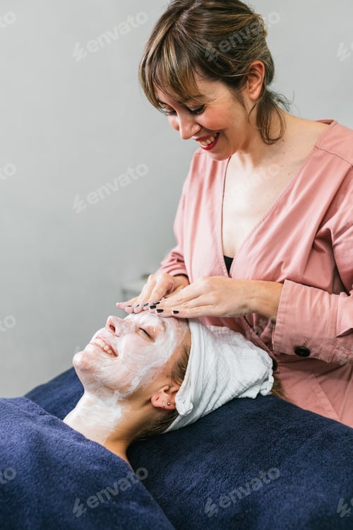 Preview: Crop beautician cleansing face of woman in salon
