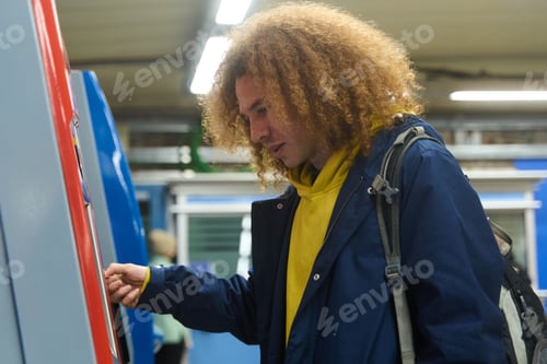 Preview: Young man using atm at train station