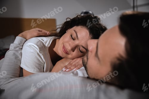 Preview: Smiling couple laying in bed and cuddles in the bedroom.