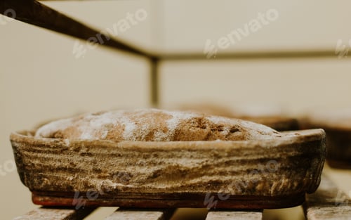 Preview: Baking bread. Dough in proofing basket on wooden table with flour, cumin and wheat ears. Top view.