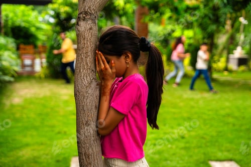 Preview: Playful Indian family enjoying hide and seek in backyard garden, sharing laughter and joy together