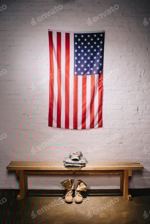 Preview: close up view of american flag hanging on white brick wall and arranged military uniform on wooden