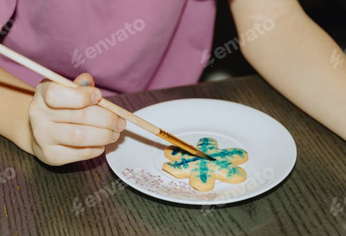 Preview: One girl is coloring cookies while sitting at the table.
