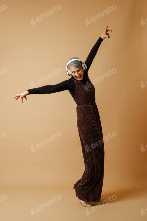 Preview: Grey senior woman dancing while listening music with headphones