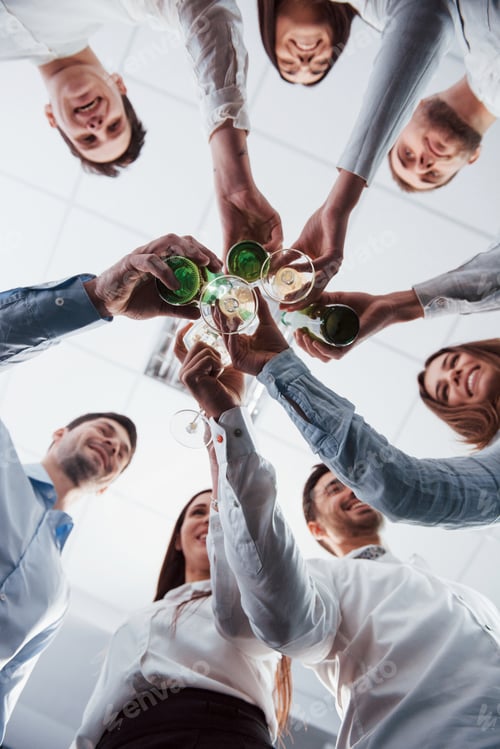 Preview: Vertical photo. View from below. Knocking glasses in the office. Celebrating success