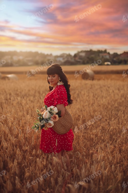Preview: Picture of a beautiful young woman walking on a large field in the evening with flowers