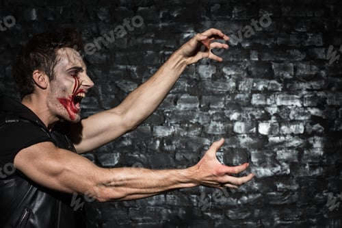 Preview: Strong zombie man stretching clawing creepy hands, while attacking someone