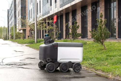 Preview: Modern automated delivery robot stands outside waiting for an order in rainy weather.