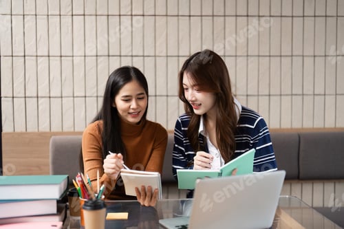 Preview: Group Study and Collaboration. Two women excitedly sharing notes and ideas during a study session.