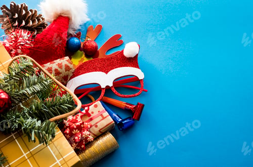 Preview: Golden shopping bag with Christmas presents, santa hat and ornaments on a blue background