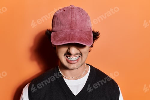 Preview: Stylish young man showcases contemporary fashion against a vibrant orange backdrop