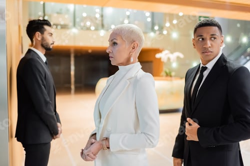 Preview: multiethnic guards escorting senior businesswoman in hotel foyer during business trip