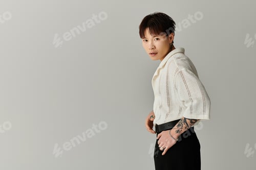 Preview: Stylish young Asian man posing confidently against a minimalistic gray backdrop