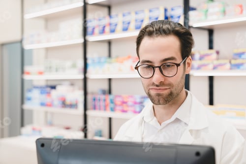 Preview: Druggist working on computer, looking at screen looking for drugs, pills for customers in drugstore