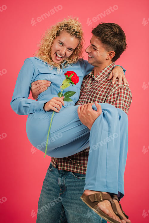 Preview: Joyful couple sharing a moment as one partner carries the other while holding a beautiful rose
