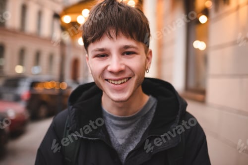Preview: Smiling handsome funny teen guy wear hoody outdoor over city lights