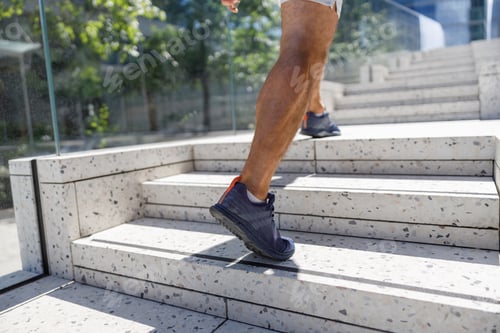 Preview: Close up legs and shoes of runner man running with sprint on the stairs in modern city