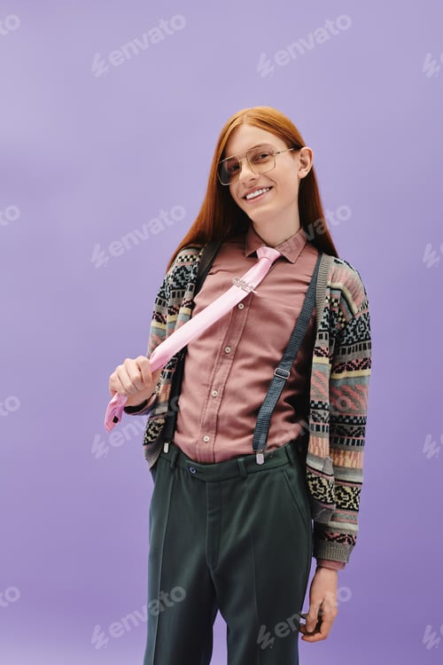 Preview: Stylish young queer man with red hair playfully adjusts his tie in a modern setting