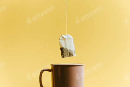 Preview: A super minimalistic shot of a bag of fast tea over a pink cup over a pastel yellow background