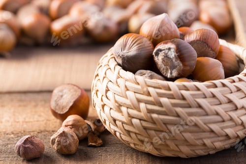 Preview: Hazelnuts in a woven basket on a wooden surface during a rustic setting