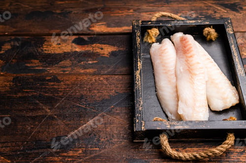Preview: Fresh fish meat, Raw cod loin pieces without skin in wooden tray. wooden background. top view