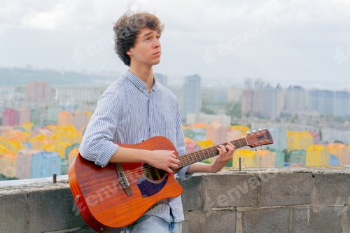 Preview: on the roof of high-rise building against the backdrop of colorful bright houses a handsome young