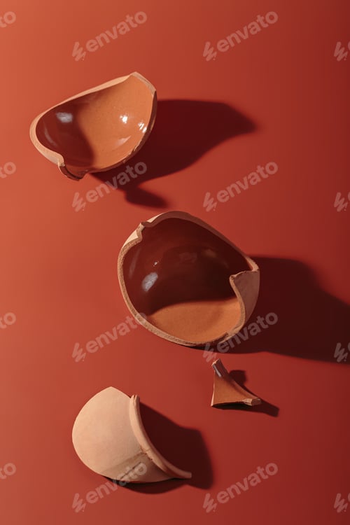 Preview: Details of broken ceramic cup on red background
