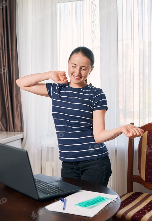 Preview: Young woman doing a little warm up after remote studying online at the computer