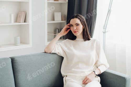 Preview: Woman Relaxing on Sofa in Bright Home Interior