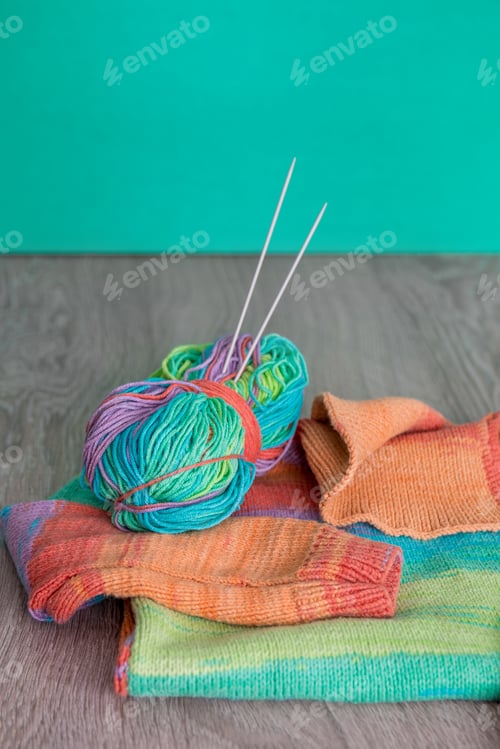 Preview: Knitting. Knitted sweater. Multicolor ball of yarn with needles near the handmade products