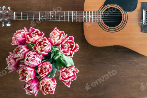 Preview: Bouquet of pink tulips and acoustic guitar on a wooden background, top view.