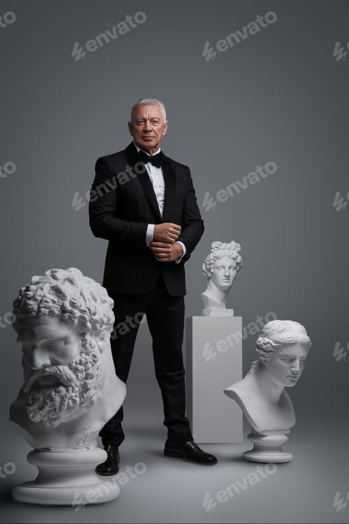 Preview: Stylish older man stands holding a gun, surrounded by three ancient sculptures