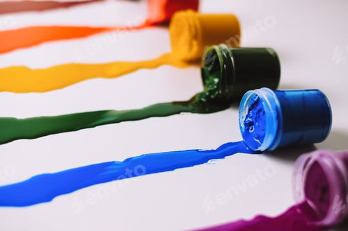 Preview: Cans with spilled paint of different colors on a white table.