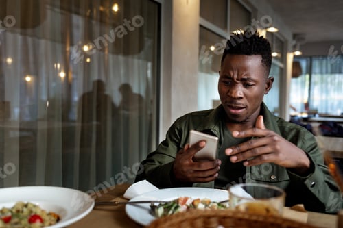 Preview: young african american man using laptop in cafe